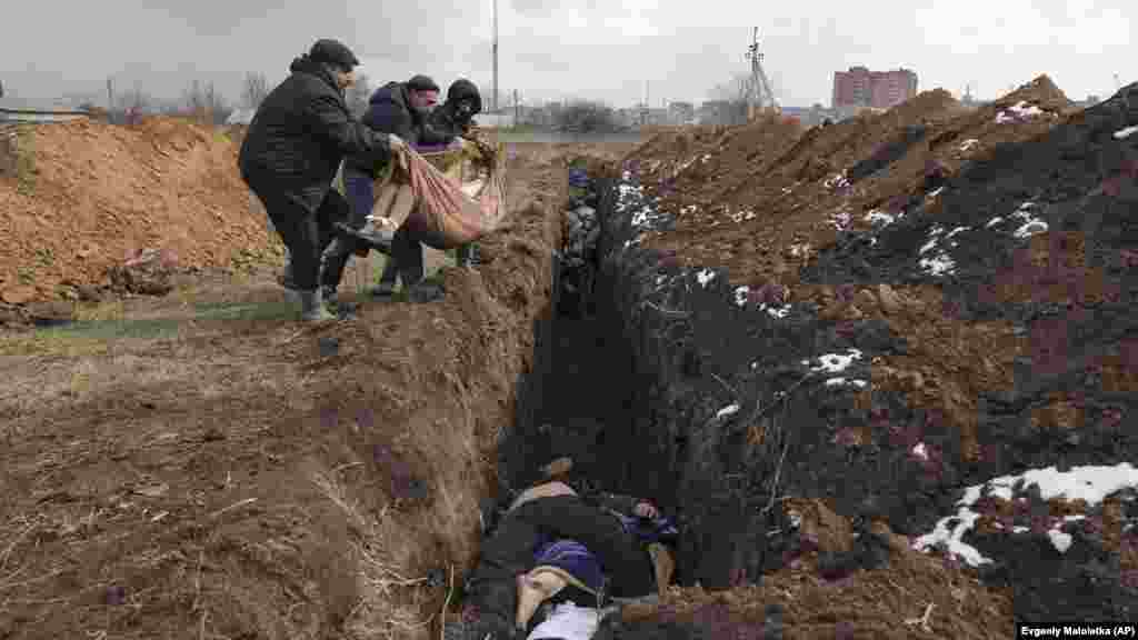 Polaganje tela u masovnu grobnicu na periferiji Mariupolja 9. marta 2022. godine. Skoro tromesečna opsada lučkog grada dovela je do smrti desetina hiljada stanovnika i uništenja 90 odsto njegove infrastrukture. &nbsp;