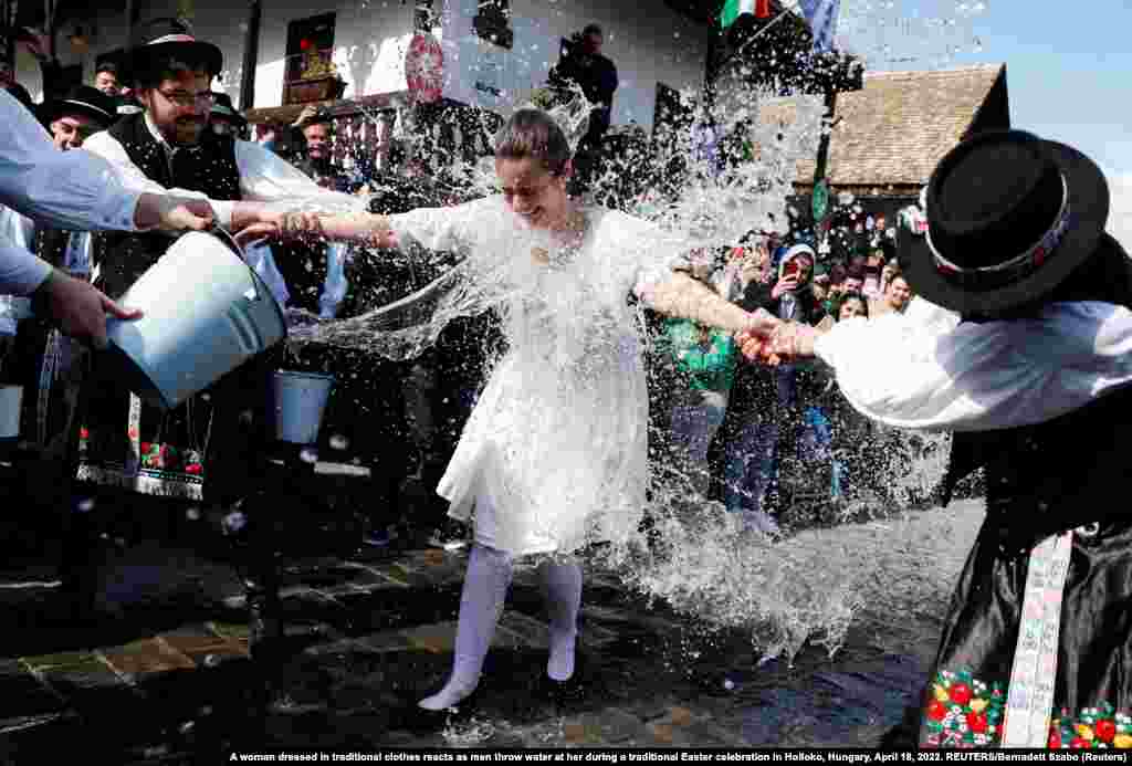 A woman dressed in traditional clothing reacts as men throw water on her during a traditional Easter celebration in Holloko, Hungary.