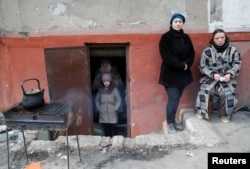 Місцеві жителі гріють воду біля входу в підвал, в якому переховуються, Маріуполь, 17 березня 2022 року