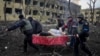 Ukrainian emergency employees and volunteers carry an injured pregnant woman from a maternity hospital after it was shelled on March 9. The woman and her unborn child later died.