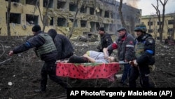 Ukrainian emergency employees and volunteers carry an injured pregnant woman from a maternity hospital after it was shelled on March 9. The woman and her unborn child later died.