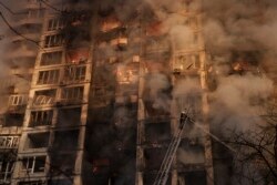 Пожарные тушат огонь в жилом доме после обстрела в Киеве 15 марта.
