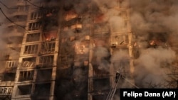 Пожарные тушат огонь в жилом доме после обстрела в Киеве 15 марта