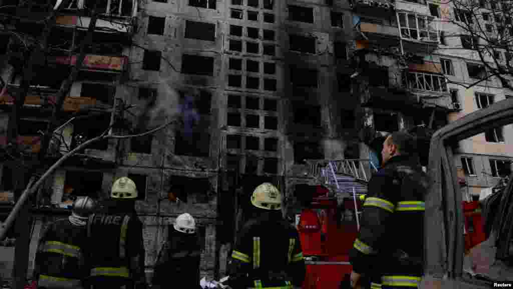 Zjarrfikësit pas ndërhyrjes, shikojnë një ndërtesë banimi që u godit nga një predhë, ndërsa sulmet e Rusisë ndaj Ukrainës po vazhdojnë, rrethi Obolon në Kiev, Ukrainë, 14 mars 2022.