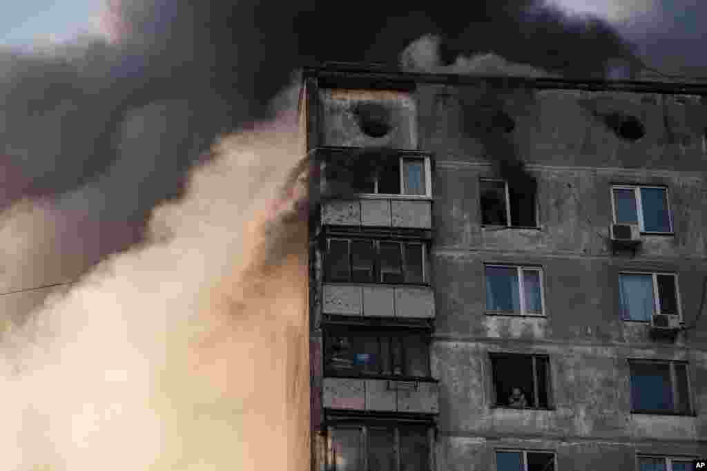 Egy bombatámadásban súlyosan megrongálódott épület egyik felső szintjén egy idős lakos várja, hogy a tűzoltók kimenekítsék&nbsp;