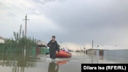 Спасатели помогают жителям села Оргебас добраться к домам на лодке, чтобы забрать документы.