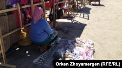 Женщина за пределами рынка торгует разложенной на земле обувью