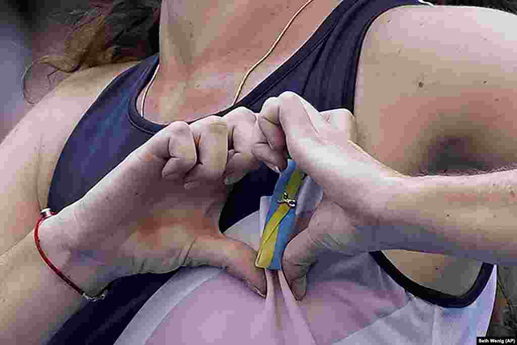Ukrainian tennis player Daria Snigur makes a heart over a pin with the colors of her country&#39;s flag after upsetting Simona Halep of Romania during the first round of the U.S. Open tennis championship.