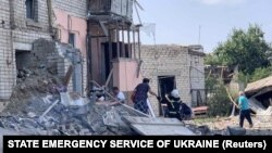 A rescuer helps a woman evacuate a residential building damaged by a Russian missile strike in Voznesensk, Mykolayiv region, on August 20.
