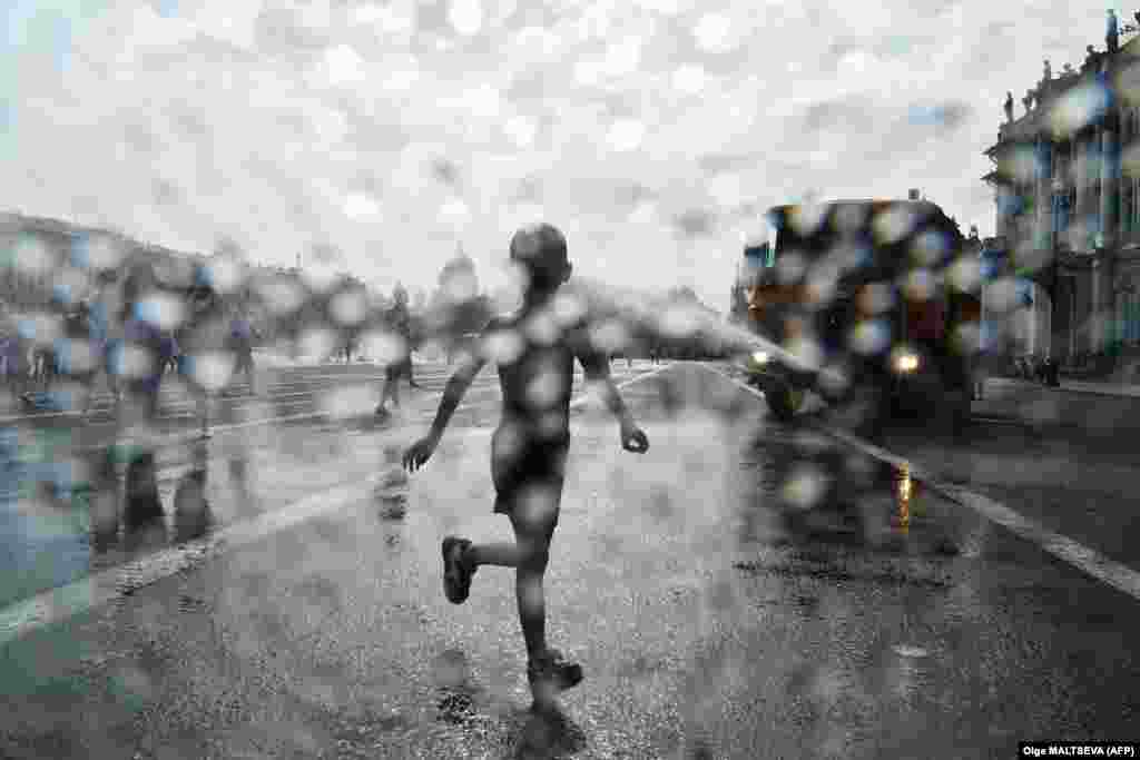 A child enjoys cooling jets as a municipal truck sprays water on Dvortsovaya Square in St. Petersburg as temperatures reached nearly 30 degrees Celsius.