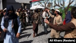 چند جنگجوی طالبان در بیرون محلی که ساکنان کابل برای دریافت بسته‌های غذایی ارسالی از عربستان به آن مراجعه کرده‌اند.