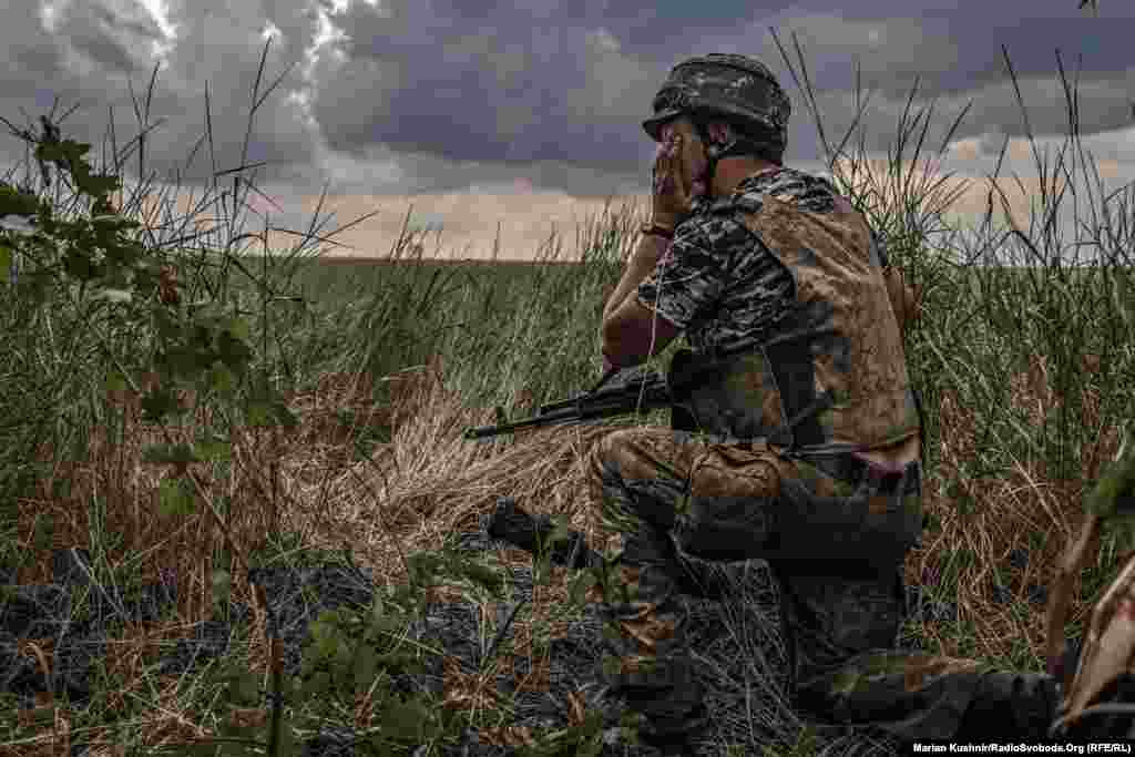 A Ukrainian soldier scans the front after firing an MT-12 Rapira anti-tank gun at Russian positions.