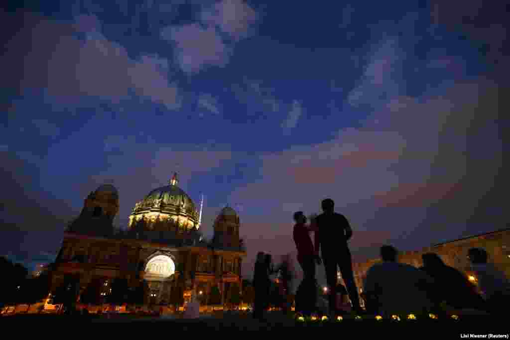 In Berlin too, historic sites stand largely unlit after sunset. People enjoy a summer evening next to Berlin&#39;s central cathedral.&nbsp; &nbsp;