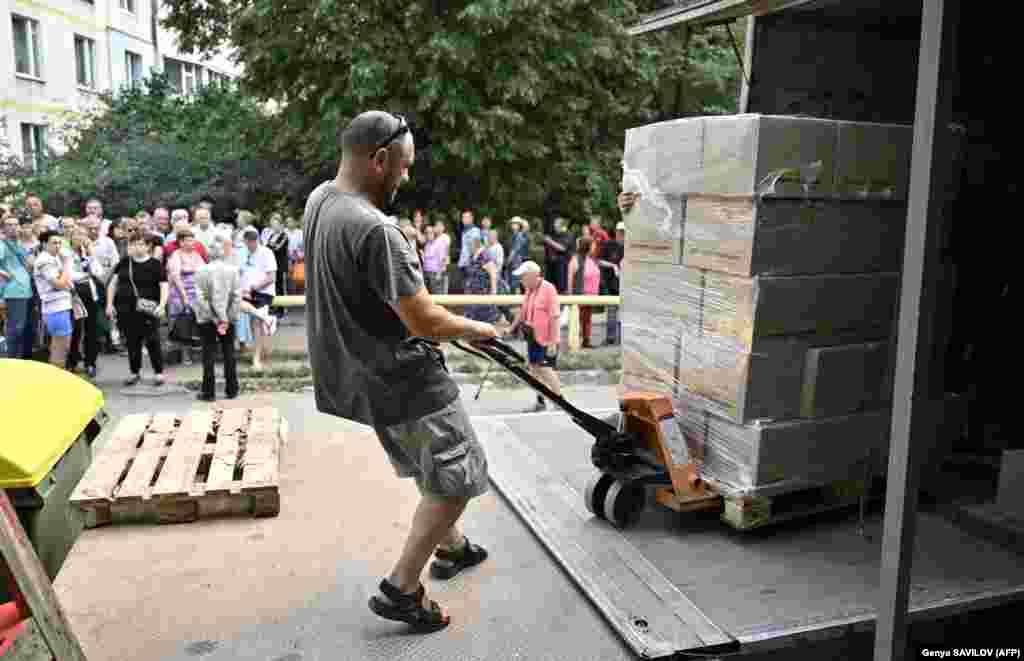 Egy önkéntes kirakodja a dobozokat a harkivi élelmiszerosztás során