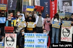 People hold placards during a protest against Russia's invasion of Ukraine, outside the Russian representative office in Taipei on March 1, 2022.