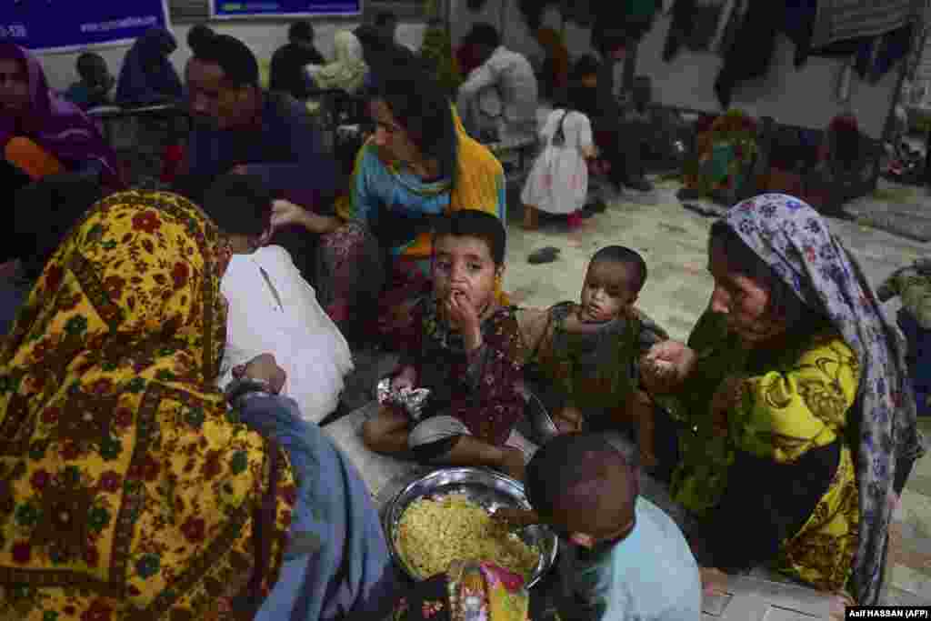 Woman and children eat food distributed by a charity in Sukkur, Sindh Province. In the midst of the massive flooding, international aid has started to arrive in Pakistan. On August 28, cargo planes from Turkey and the United Arab Emirates arrived with tents, food, and other supplies.