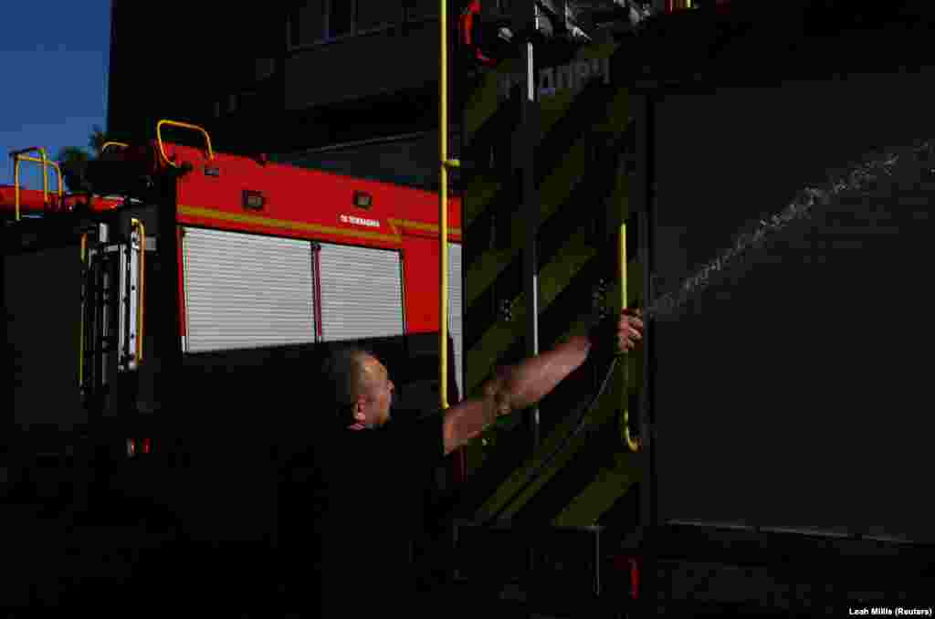 Пожежник рано вранці обливає водою дві вантажівки на пожежній частині у Харкові, 1 липня 2022 року