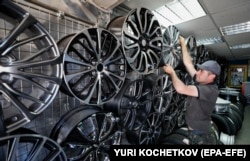 Salesman will adjust wheel rims at Moscow's auto parts market in June 2022.