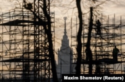 Construction laborers work on scaffolding in the Russian capital with the Moscow State University building in the background. (file photo)