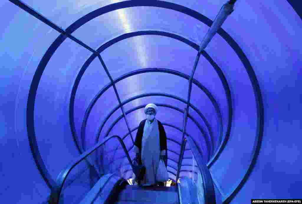 An Iranian cleric takes a pedestrian bridge on a street in Tehran.