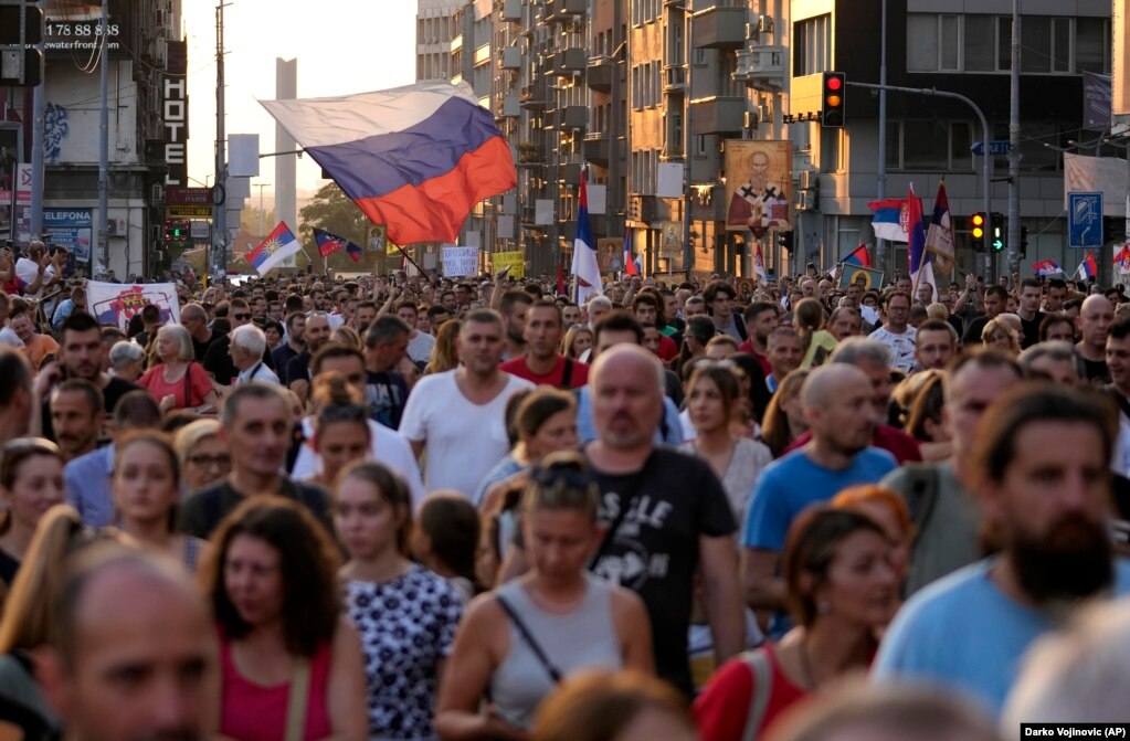 Një flamur rus i ngritur mbi turmën gjatë protestës. Vuçiq ka thënë se qeveria është përballur me trysni të madhe nga grupet djathtiste dhe përfaqësuesit e Kishës Ortodokse Serbe për të anuluar ngjarjen. Ai ka lënë hapur mundësinë që ngjarja të mbahet në një datë të mëvonshme.
