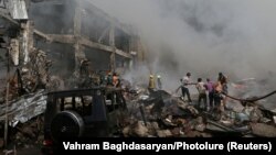 People help firefighters extinguish a fire after blasts ripped through a fireworks warehouse at a shopping mall in Yerevan on August 14.