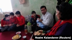 An Afghan refugee in Tajikistan sits with his family in their apartment in the Tajik town of Vakhdat in 2010.