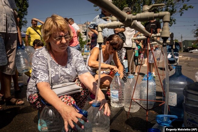 Një grua mbush ujë në shishet e ofruara nga organizata vullnetare e Odesës në Mikolajiv, 8 gusht 2022.