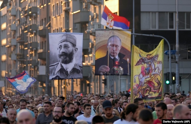 Protesters in Belgrade on August 28 march in opposition to planned LGBT celebrations while carrying Russian flags and a picture of Russian President Vladimir Putin (right) and controversial Serb World War II General Dragoljub Mihailovic