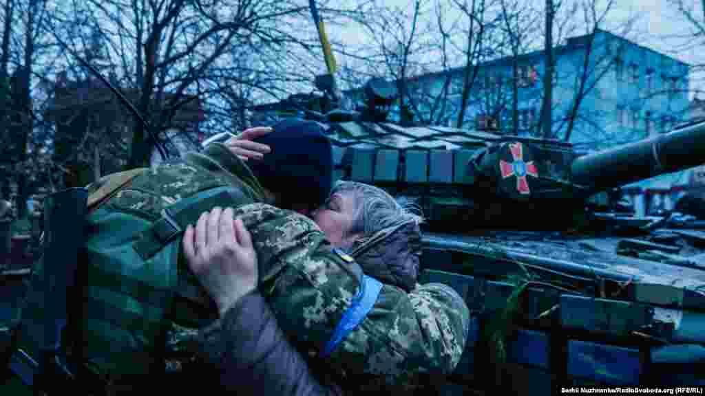 Жінка обнімає оборонця України біля бойової машини ЗСУ під українським прапором. Бахмач, Чернігівщина