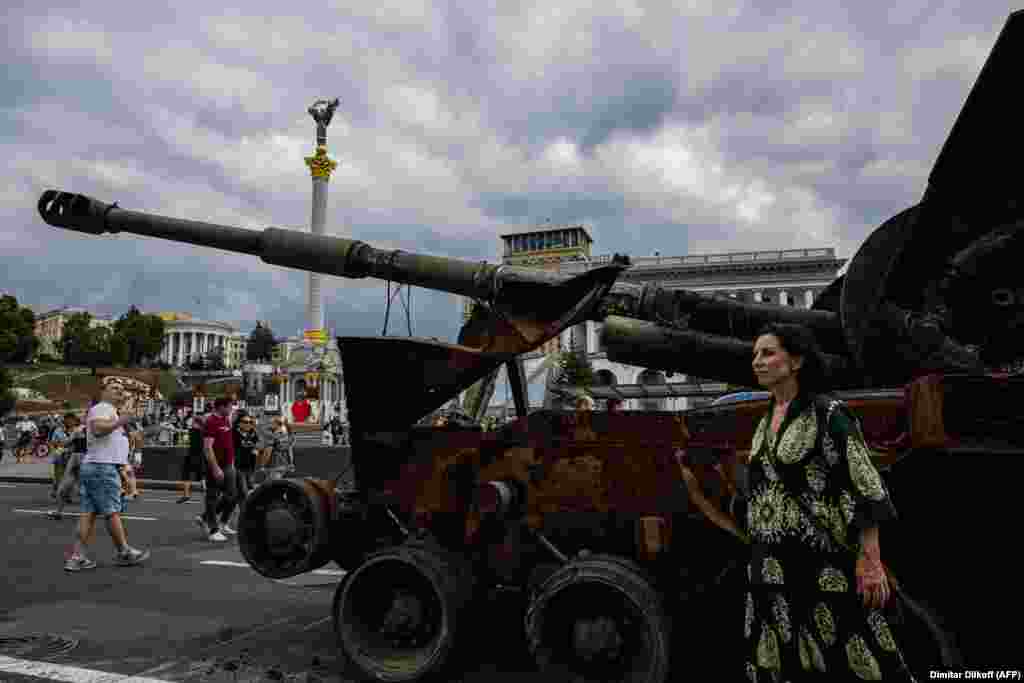 Egy nő fotózkodik egy orosz harckocsi maradványaival