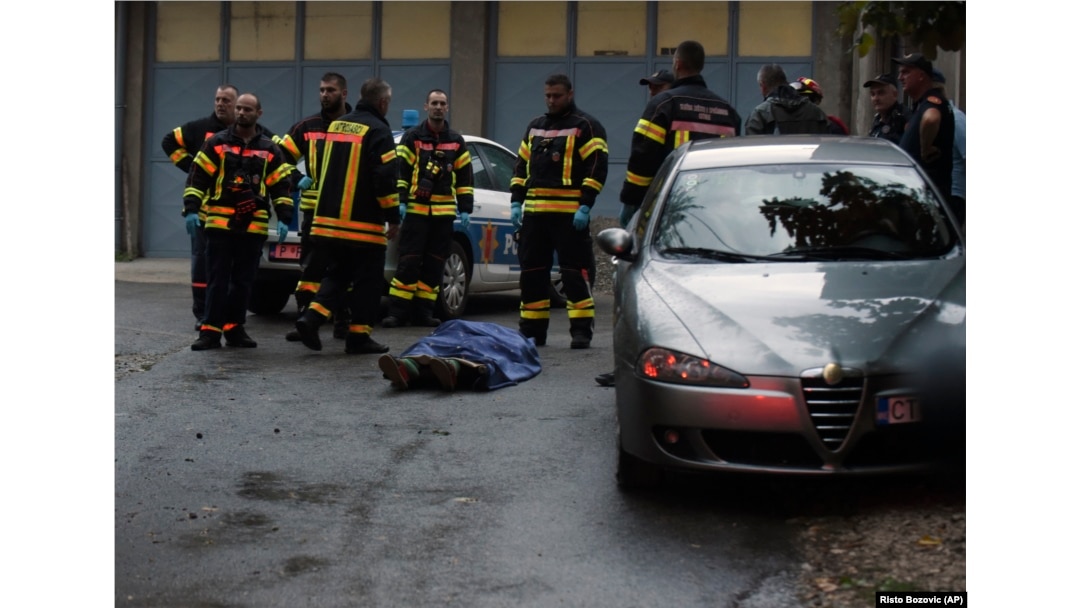 Firefighters stand next to the body of one of the victims of the August 12 attack in Cetinje.