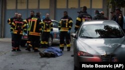 Vatrogasci stoje uz telo na mestu pucnjave u kojoj je život izgubilo 11 osoba u Cetinju u Crnoj Gori 12. avgusta 2022. 