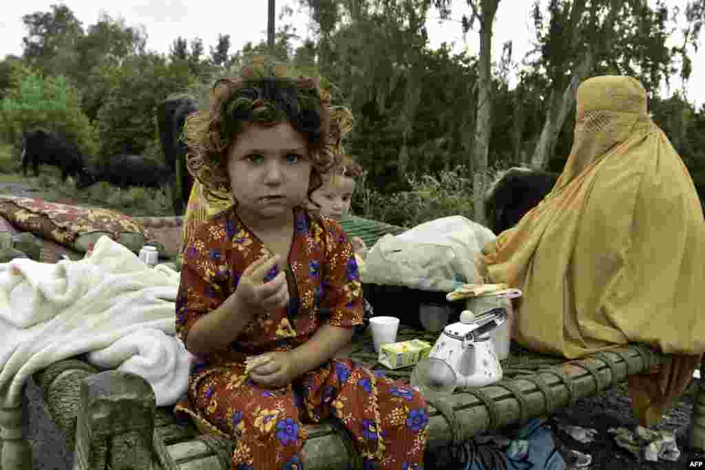 Persoane strămutate se refugiază de-a lungul unei autostrăzi după ce au fugit din casele lor afectate de inundații în urma ploilor musonice puternice din districtul Charsadda, în provincia Khyber Pakhtunkhwa din Pakistan, la 27 august 2022.