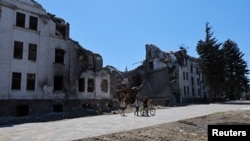  Люди проходят мимо здания театра, разрушенного во время украинско-российского конфликта в южном портовом городе Мариуполь, Украина, 15 июля 2022 года.