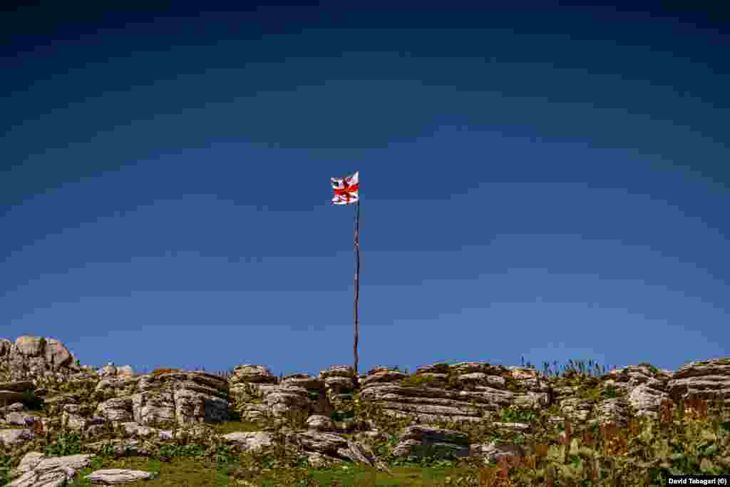Грузинский флаг в горах. Летний сезон для производителей сулугуни относительно короткий. К началу осени мужчины отгонят свое стадо вниз, на равнины, чтобы спасти животных от лютых морозов в горах