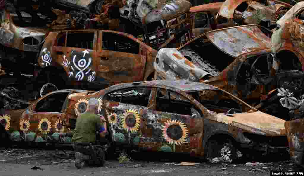 A Ukrainian soldier crosses himself at a symbolic cemetery of cars shot up by Russian troops, some painted by local artists, in Irpin, outside Kyiv.