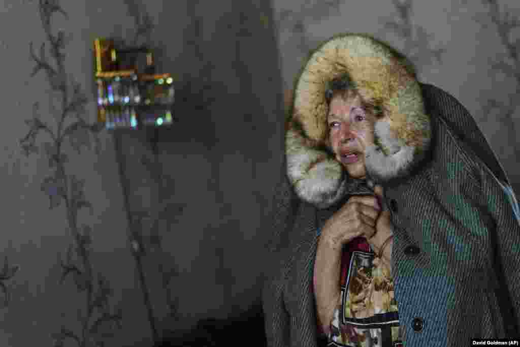 Lyubov Mahliy demonstrates how she takes a coat and wraps it around her for protection when air-raid sirens go off in her apartment in Slovyansk in Ukraine&#39;s eastern Donetsk region.