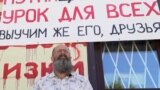 Dmitry Skurikhin in front of his store that is painted with the names of Ukrainian cities that have been bombed