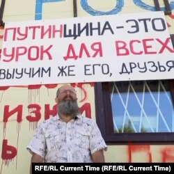 Dmitry Skurikhin stands in front of his store in August, which is painted with the names of Ukrainian cities that have been bombed.