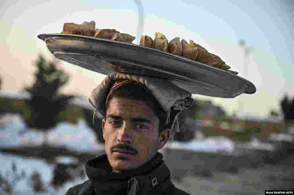 An Afghan man carries samosas for sale on his head at the Hill of Wazir Akbar Khan in Kabul.&nbsp;