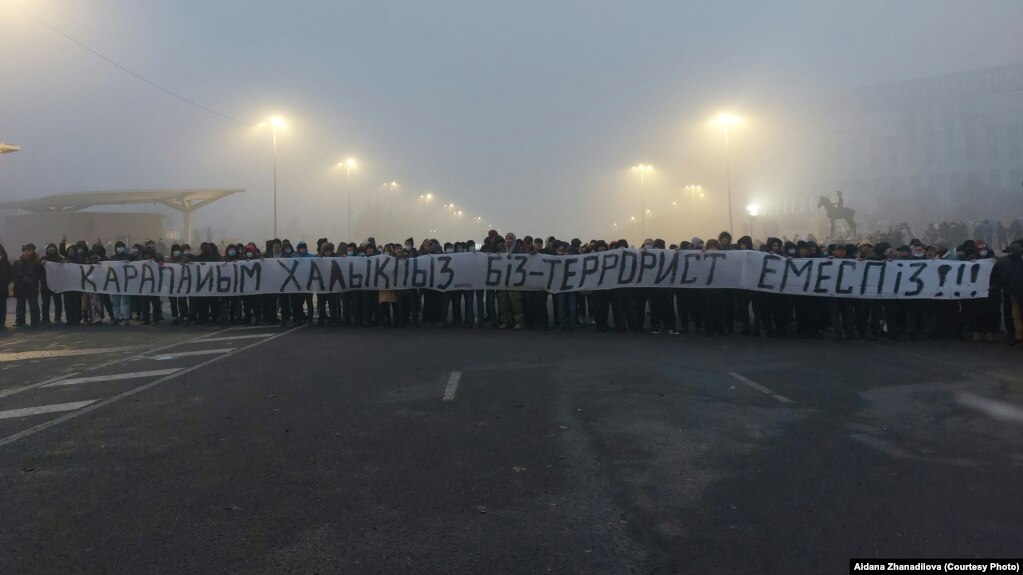 Республика алаңында "Қарапайым халықпыз. Біз — террорист емеспіз!" деген жазу ұстап тұрған адамдар. Алматы, 6 қаңтар 2022 жыл.