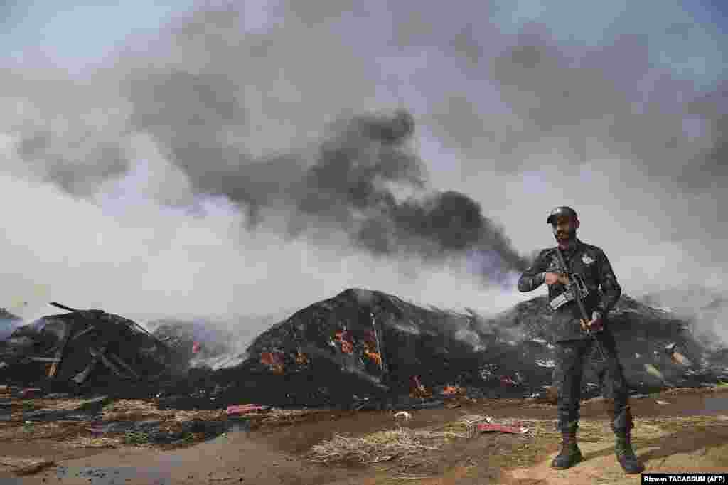 A customs official stands guard during an event organized to destroy seized illicit alcohol and drugs that had been smuggled into the country, in Karachi, Pakistan.​