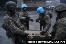 Kazakh soldiers wearing blue "UN" helmets pick out flash-bang grenades in Almaty on January 6. Arm badges on the servicemen are those of the Kazakh military.