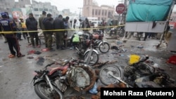 Members of a crime scene unit and a bomb disposal team gather after a blast at a market in Lahore on January 20.
