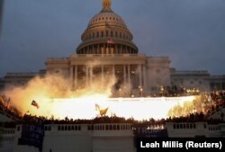 O explozie provocată de o muniție a poliției este văzută în timp ce susținători ai lui Donald Trump se adună în fața clădirii Capitoliului american din Washington, 6 ianuarie 2021.