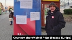 Activist Peter Heindl stands next to a poster promoting the Hungarian government's slogan of "Hungary goes forward! Not backward!" in 2021. He says the billboards are unconstitutional and has reported the campaign to prosecutors.