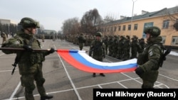 Российские солдаты складывают национальный флаг во время церемонии, посвященной началу вывода сил ОДКБ из Казахстана 13 января