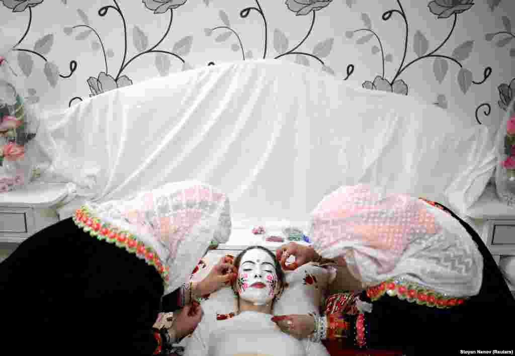 Muslimanska nevesta Kimile Avdinova koju šminkaju tokom ceremonije venčanja u selu Ribnovo u Bugarskoj. Zabačeno planinsko selo je održalo svoju tradicionalnu zimsku ceremoniju venčanja uprkos decenijama komunističkog progona. Vrhunac ceremonije je oslikavanje nevestinog lica, gde je u privatnom obredu koji je otvoren samo za svekrve, njeno lice prekriveno gustom, kredasto belom bojom i ukrašeno šarenim šljokicama.