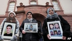 Samaa Mahmoud, Mariam Alhallak și Yasmen Almashan cu imagini ale rudelor lor ucise în Siria, înainte de verdictul tribunalului din Koblenz, Germania, în procesul lui Anwar Raslan, 13 ianuarie 2022.